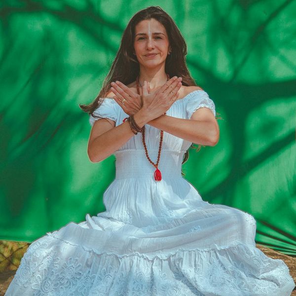 Person sitting in a meditative yoga pose against a calm, minimal background.